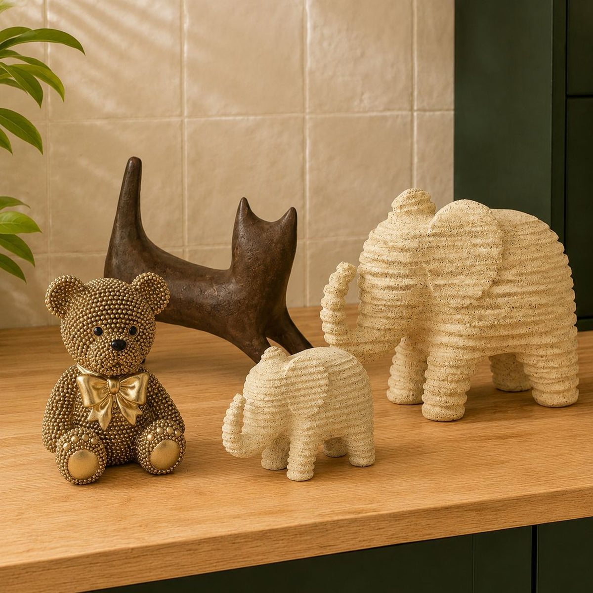 Gouden teddybeer met strik, bruin abstract kattenbeeld en twee beige geribbelde olifantenbeelden op een houten kast