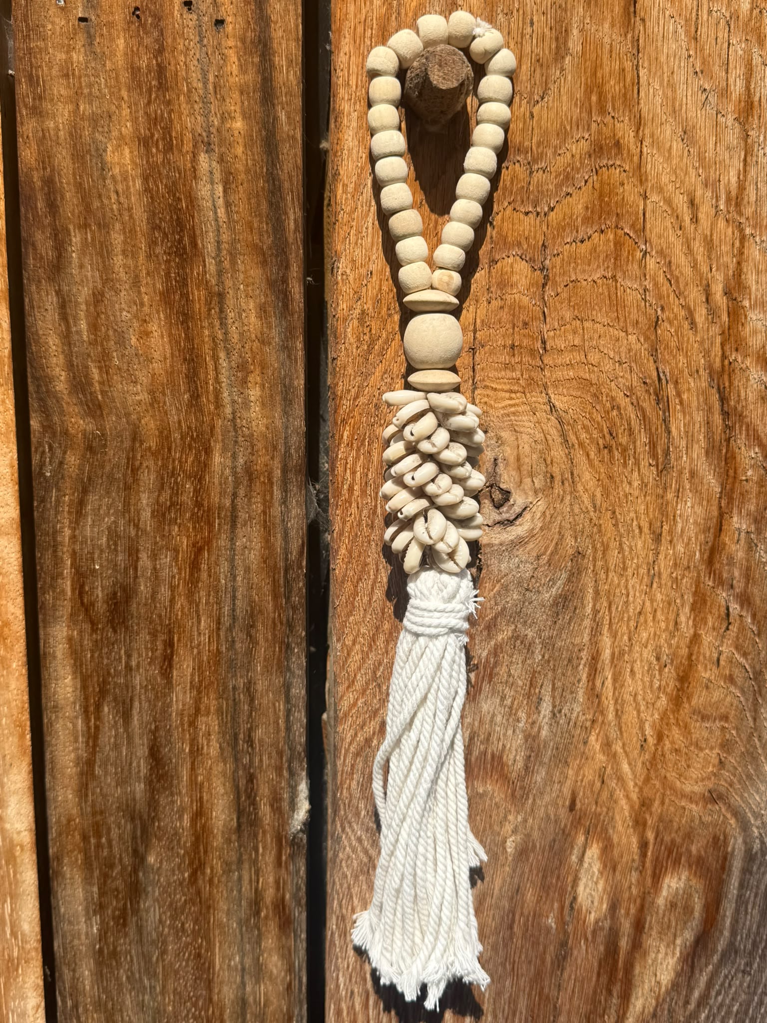 Schelpenhanger met houten kralen en tassel aan houten wand in Bali stijl
