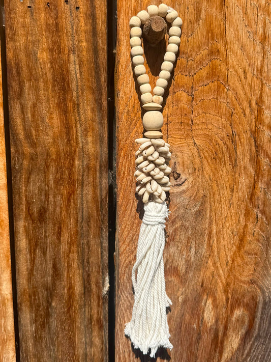 Schelpenhanger met houten kralen en tassel aan houten wand in Bali stijl