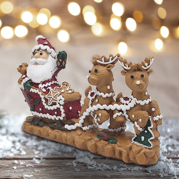 Gingerbread kerstbeeld van polyresin met kerstman in versierde slee en twee bruine rendieren met witte glazuurdetails, circa 21 cm breed.