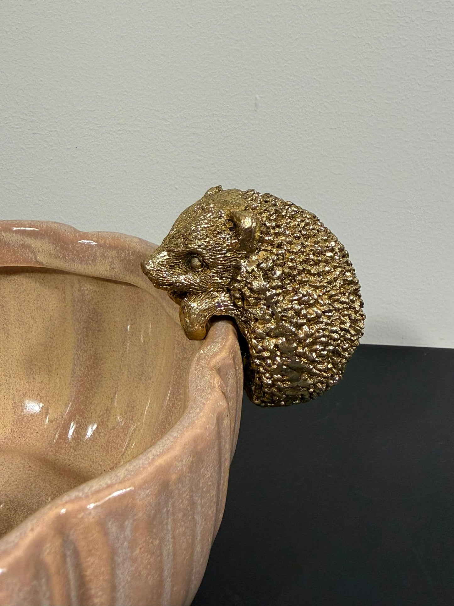 Gouden egel randhanger van polyresin aan de rand van een decoratieve schaal