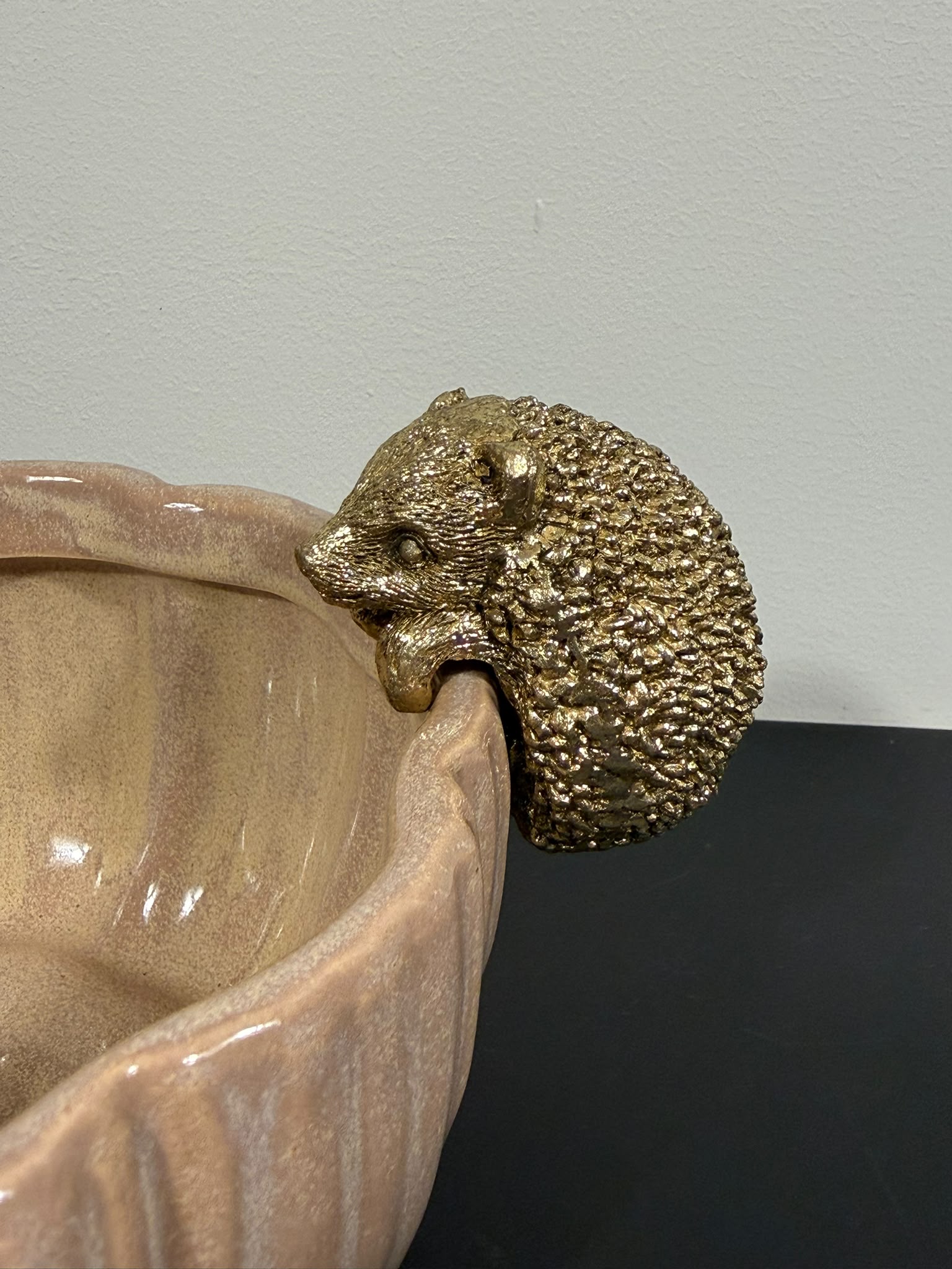 Gouden egel randhanger van polyresin aan de rand van een decoratieve schaal