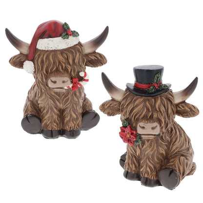 Twee Schotse hooglander kerstbeeldjes van polyresin met lange bruine vacht en horens, één met rode kerstmuts en één met zwarte hoge hoed, 11 cm