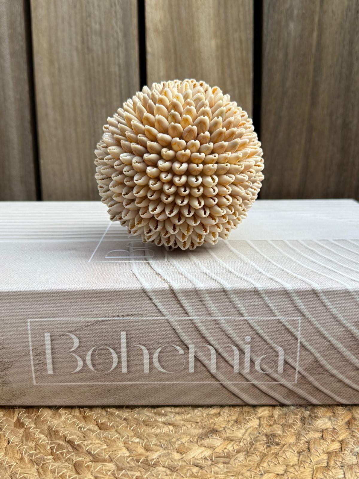 Naturel crème decoratiebol van kaurischelpen op koffietafelboek als Bali woondecoratie