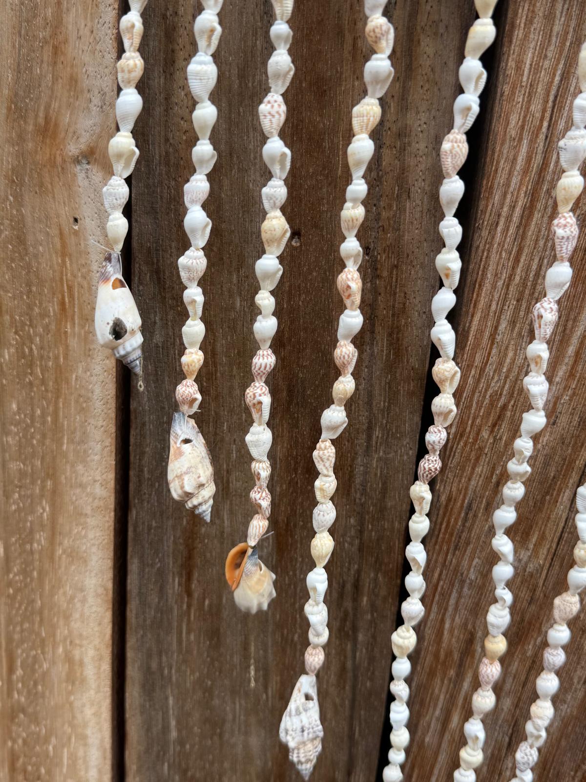Detail van lange hangers met kleine natuurlijke schelpen onder olifant wanddecoratie