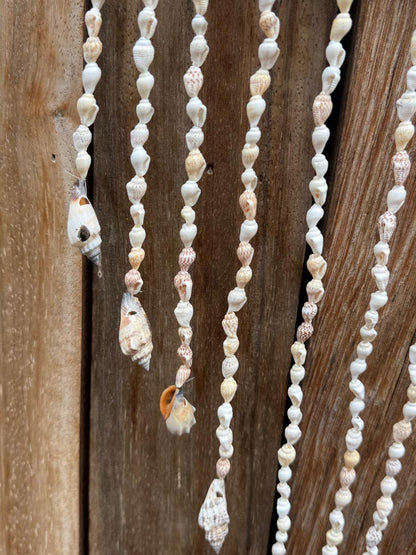 Detail van lange hangers met kleine natuurlijke schelpen onder olifant wanddecoratie